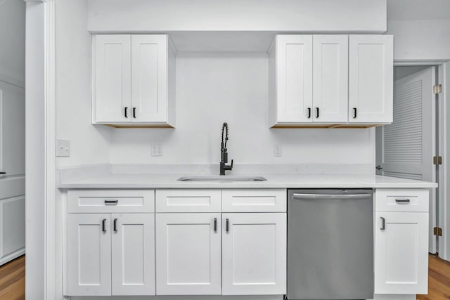 kitchen with sink, light hardwood / wood-style flooring, stainless steel dishwasher, light stone countertops, and white cabinetry