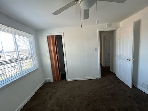 unfurnished bedroom featuring ceiling fan and dark colored carpet