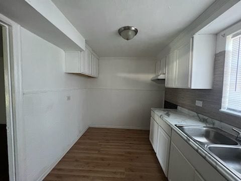 kitchen with dark hardwood / wood-style flooring, decorative backsplash, sink, and white cabinets