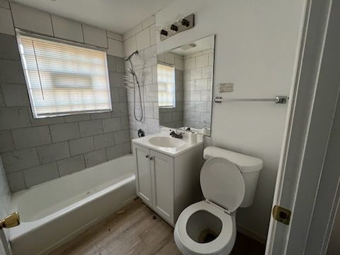 full bathroom with tiled shower / bath, toilet, vanity, and hardwood / wood-style flooring