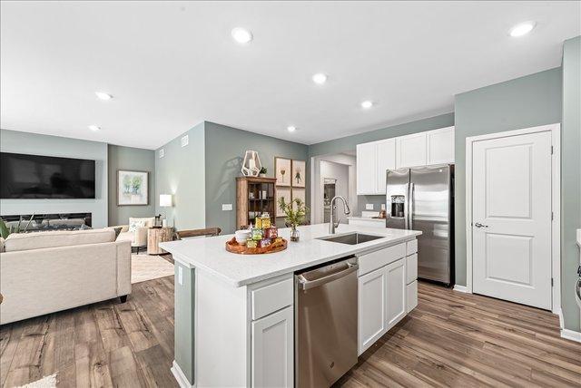 kitchen with white cabinets, sink, stainless steel appliances, and a kitchen island with sink