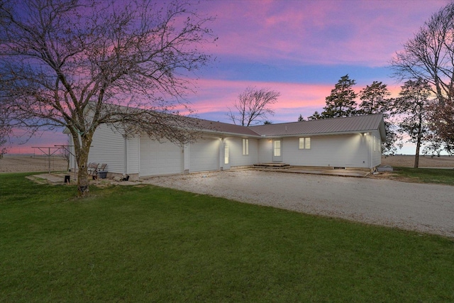 view of front of property featuring a front yard, gravel driveway, metal roof, and an attached garage