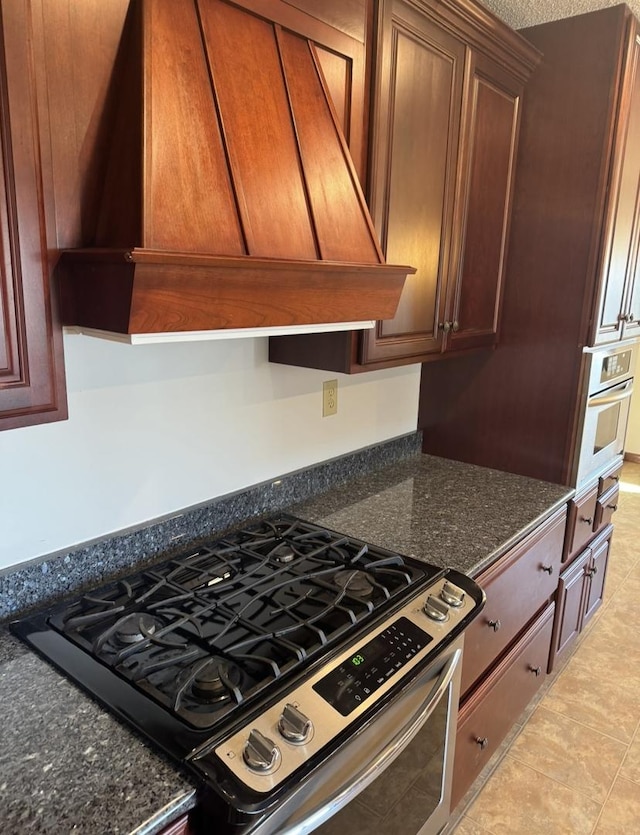 kitchen featuring appliances with stainless steel finishes, premium range hood, and dark stone countertops