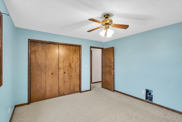 unfurnished bedroom with light carpet, a textured ceiling, a closet, and ceiling fan