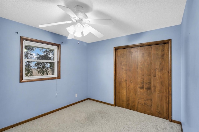 unfurnished bedroom with ceiling fan, a closet, light carpet, and a textured ceiling