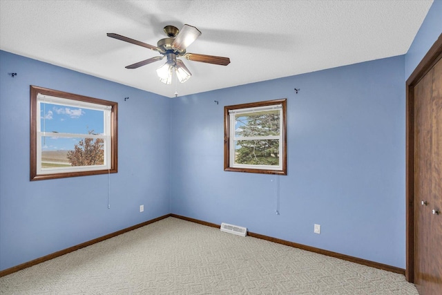 empty room featuring carpet floors, visible vents, ceiling fan, and baseboards