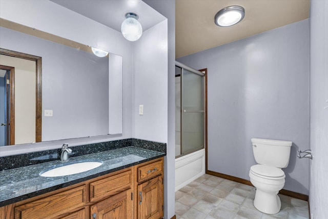 bathroom featuring baseboards, combined bath / shower with glass door, vanity, and toilet