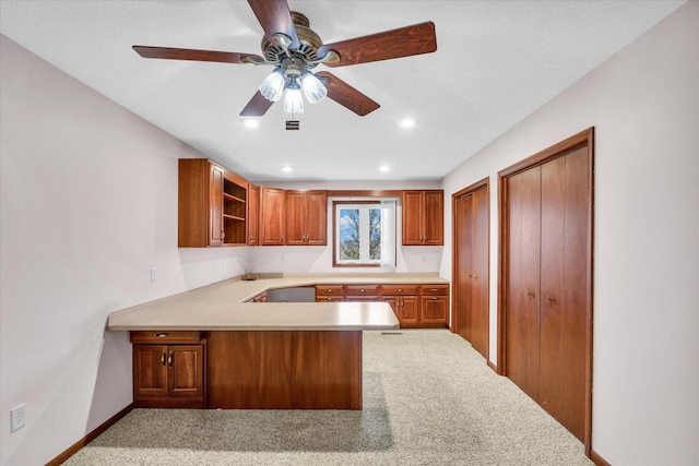 kitchen with kitchen peninsula, light carpet, and ceiling fan