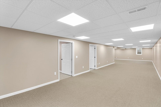 basement featuring a paneled ceiling and light colored carpet