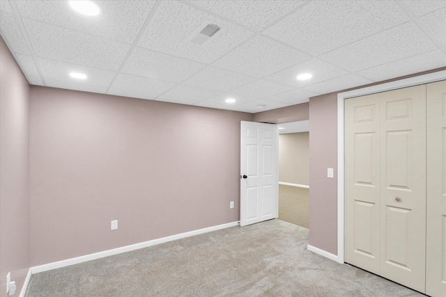 basement featuring a paneled ceiling and light carpet