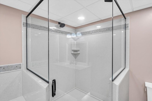 bathroom with a drop ceiling and a shower with door