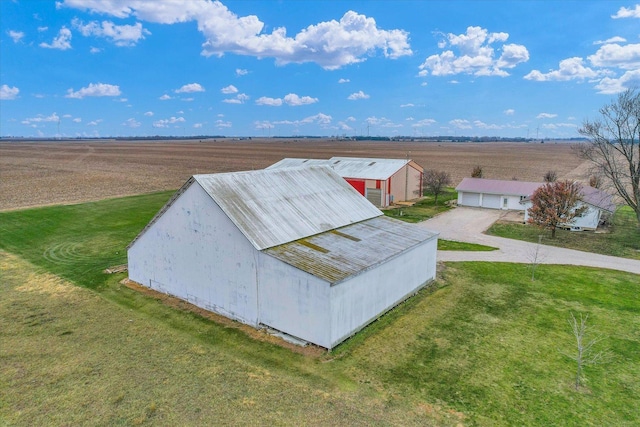 entry to storm shelter with a lawn, a rural view, and an outbuilding