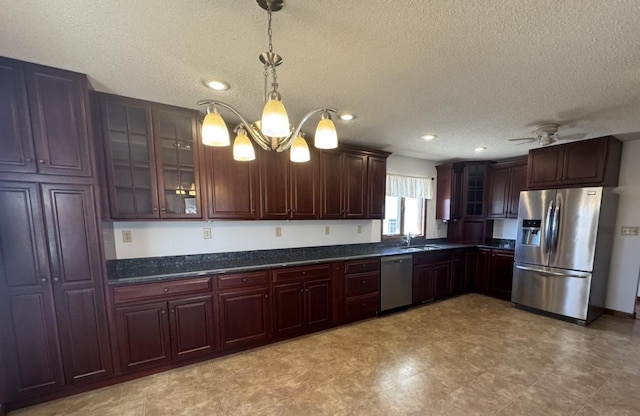 kitchen with a textured ceiling, decorative light fixtures, ceiling fan with notable chandelier, stainless steel appliances, and glass insert cabinets