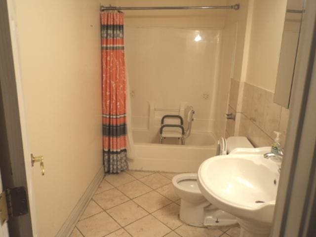 full bathroom featuring sink, tile patterned floors, shower / bath combination with curtain, toilet, and tile walls