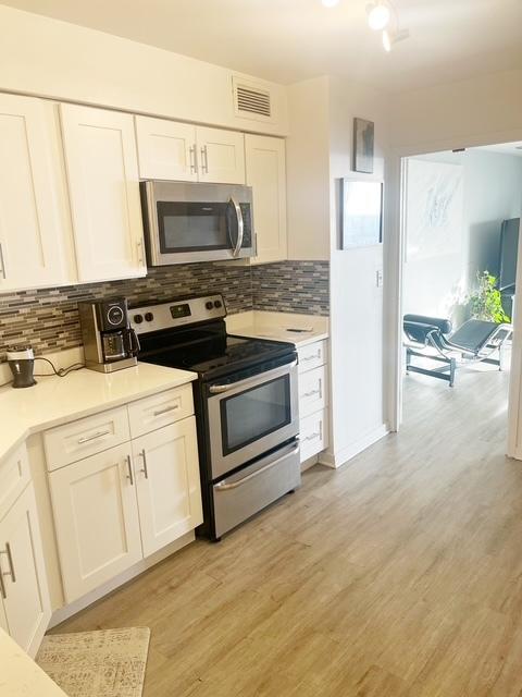 kitchen featuring tasteful backsplash, white cabinets, stainless steel appliances, and light hardwood / wood-style floors