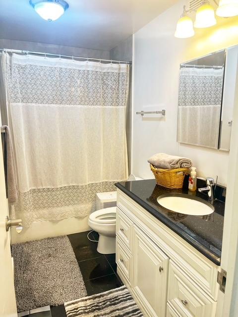 bathroom with tile patterned floors, a shower with curtain, vanity, and toilet