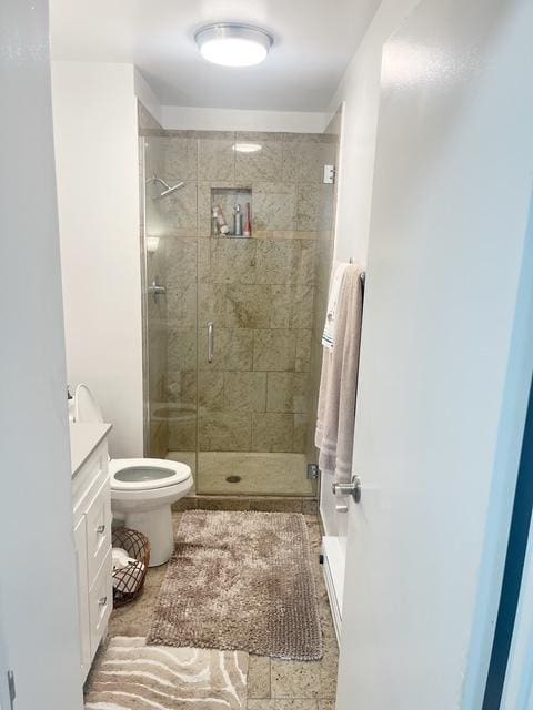 bathroom featuring vanity, a shower with shower door, and toilet