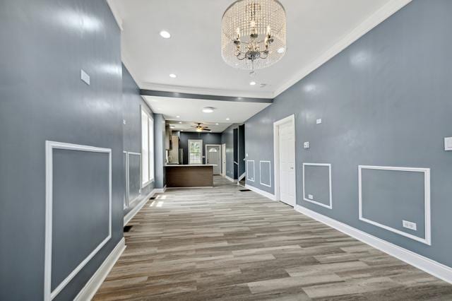 corridor featuring a chandelier, crown molding, and light hardwood / wood-style floors