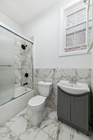 full bathroom featuring toilet, vanity, tile walls, and combined bath / shower with glass door