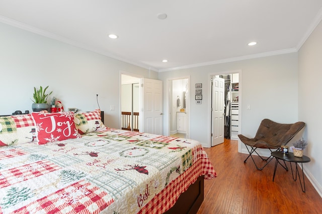 bedroom with hardwood / wood-style floors, ensuite bath, and crown molding