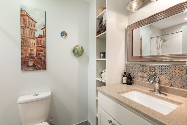 bathroom featuring tasteful backsplash, vanity, tiled shower, and toilet