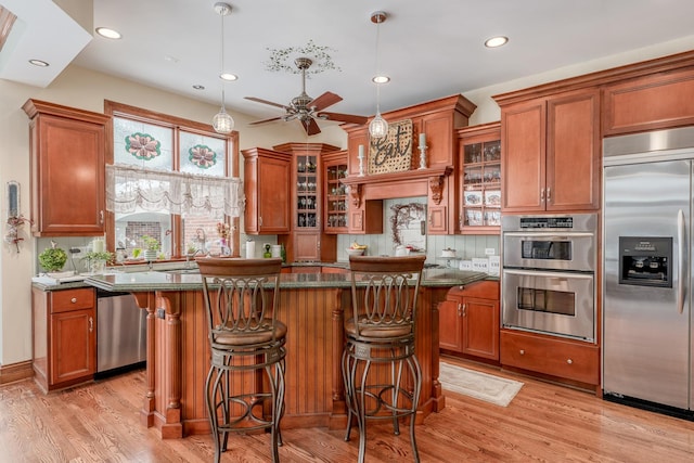 kitchen featuring ceiling fan, a kitchen island, light wood-type flooring, and stainless steel appliances