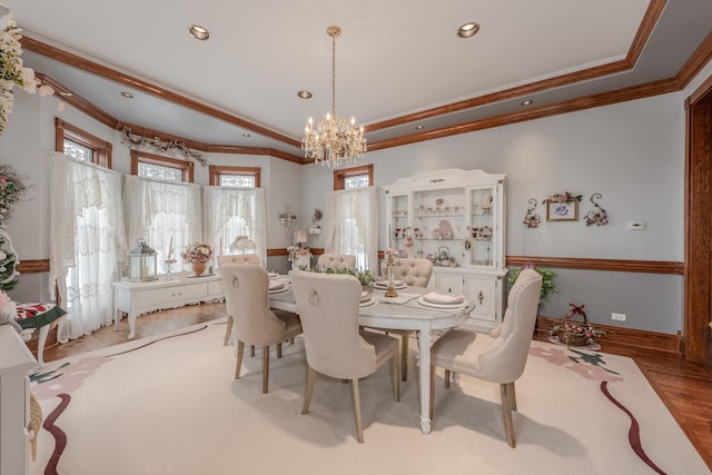 dining area with light wood-type flooring, crown molding, a tray ceiling, and a chandelier