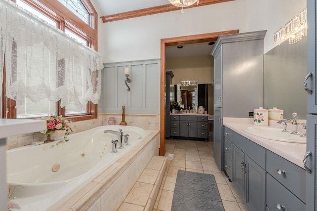 bathroom with tile patterned flooring, vanity, lofted ceiling, and tiled tub