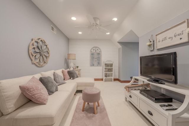 carpeted living room featuring vaulted ceiling, ceiling fan, and wood walls