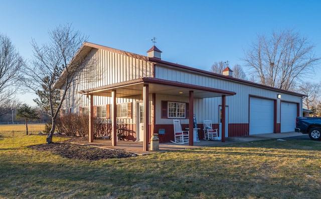 rear view of property with a yard, a porch, and a garage