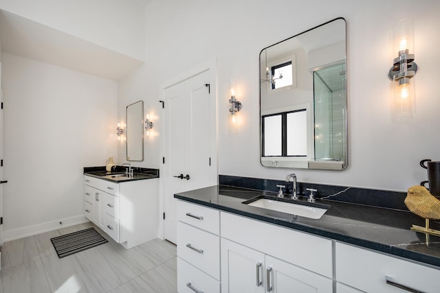 bathroom featuring two vanities, baseboards, and a sink