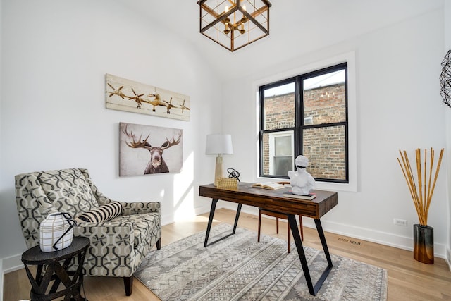 office area with wood finished floors, visible vents, baseboards, an inviting chandelier, and vaulted ceiling