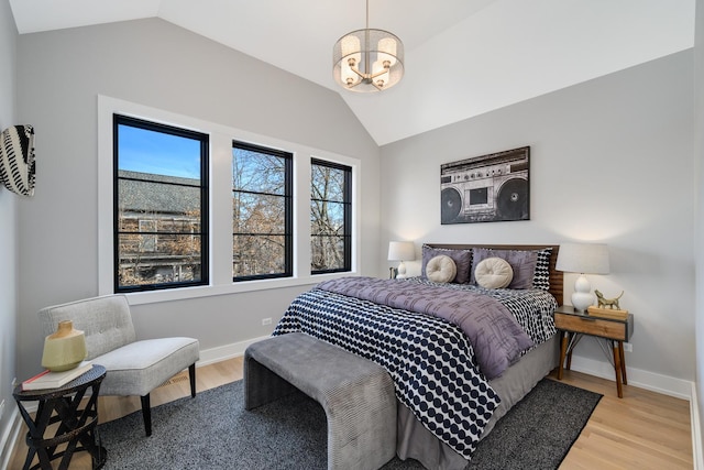 bedroom featuring baseboards, light wood-style floors, and vaulted ceiling