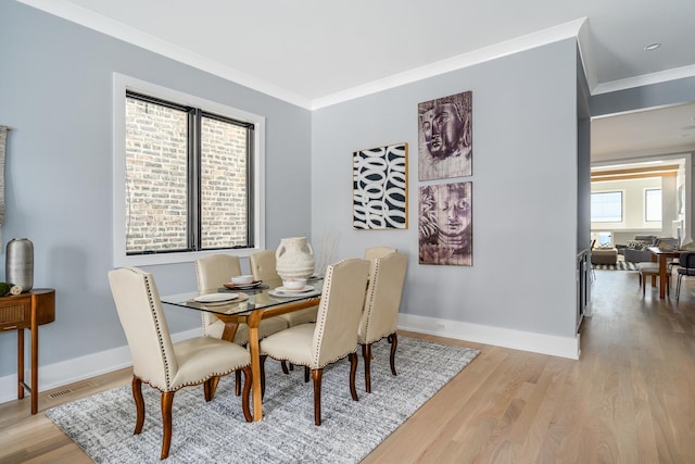 dining space featuring baseboards, wood finished floors, visible vents, and ornamental molding