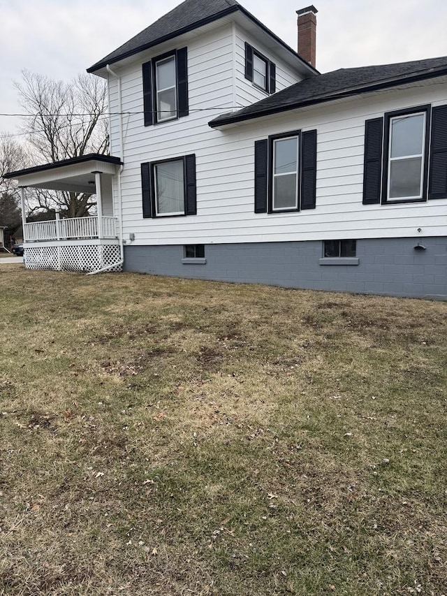 view of side of home with a lawn and covered porch