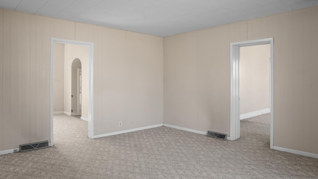 spare room featuring carpet floors, visible vents, and arched walkways