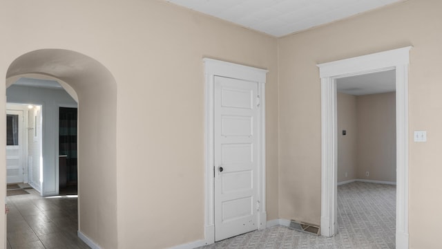 hallway featuring arched walkways and baseboards