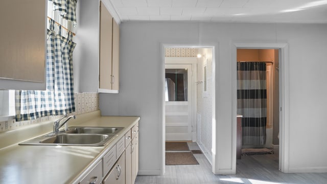 kitchen with light countertops, decorative backsplash, a sink, and baseboards