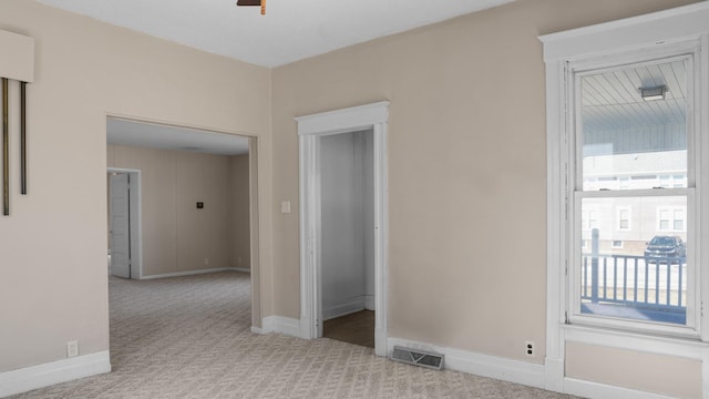 unfurnished room featuring a ceiling fan, carpet, visible vents, and baseboards