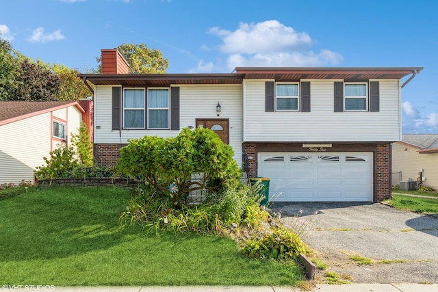 raised ranch with central AC unit, a garage, and a front yard