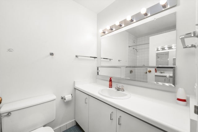 bathroom featuring tile patterned floors, vanity, a tile shower, and toilet