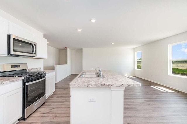 kitchen featuring white cabinetry, sink, light hardwood / wood-style floors, a center island with sink, and appliances with stainless steel finishes