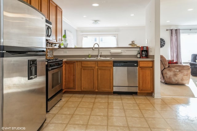 kitchen with appliances with stainless steel finishes, ornamental molding, and sink