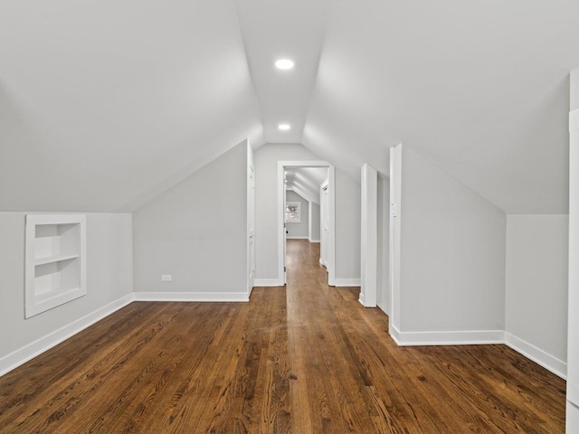 bonus room with dark hardwood / wood-style floors, vaulted ceiling, and built in shelves