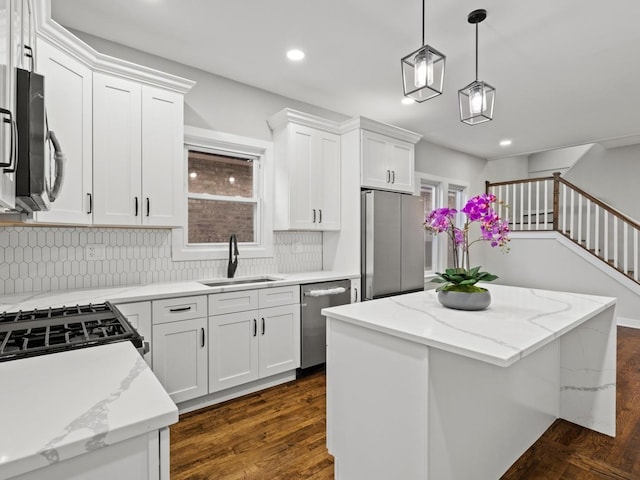 kitchen featuring appliances with stainless steel finishes, a center island, white cabinetry, and sink