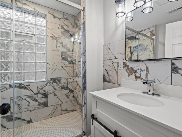 bathroom with a tile shower, vanity, and tile walls