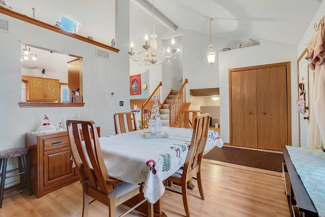 dining area with lofted ceiling with beams, light hardwood / wood-style floors, and an inviting chandelier