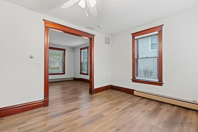 unfurnished room featuring light hardwood / wood-style floors, ceiling fan, and a baseboard heating unit