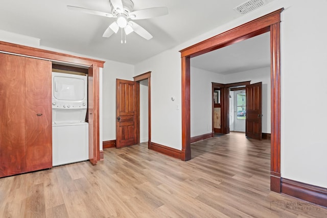 unfurnished bedroom featuring ceiling fan, stacked washer / dryer, and light hardwood / wood-style flooring