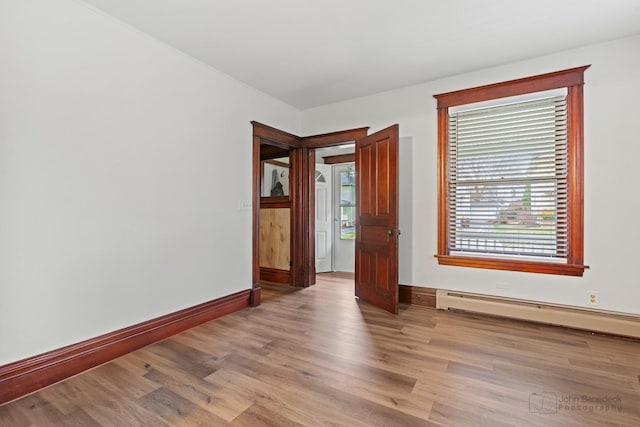 empty room featuring baseboard heating and light hardwood / wood-style floors